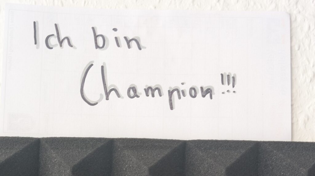 Handgeschriebener Zettel mit den Worten Ich bin Champion und drei Ausrufezeichen über einem Bildschirm